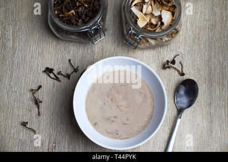 Soupe aux champignons dans un bol et les contenants de verre avec des champignons séchés Banque D'Images