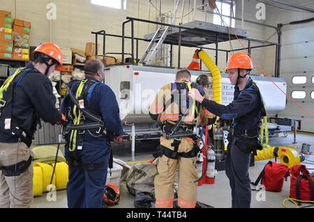 PATUXENT RIVER (fév. 21, 2019) - Les pompiers de Patuxent River NAS se préparent à être descendu dans un trou étroit le 21 février, de 33 heures au cours d'un sauvetage technique/formation en espace clos de la classe. À l'aide d'un réservoir de carburant en aluminium comme un accessoire, les pompiers ont été adaptés dans les faisceaux avec corde et appareil respiratoire et abaissé par winch dans un étroit trou dans le réservoir. Les espaces confinés à Pax River peuvent inclure des trous, des puits, des réservoirs d'eau, d'aéronefs et les sous- ou l'espace au-dessus du niveau du sol. Banque D'Images