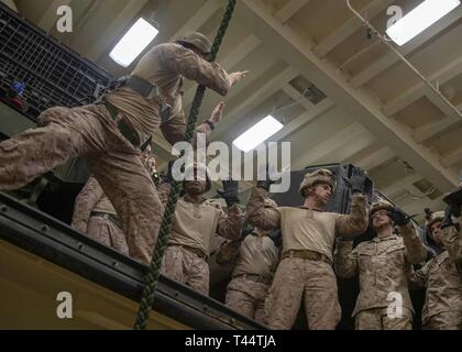 Mer Méditerranée, 10 févr. 22, 2019 - Le Sergent des Marines des États-Unis. Joshua Rose, un chef d'équipe et les techniques de suspension corde d'hélicoptères affectés à la 22e maître Marine Expeditionary Unit, indique à Marines et marins sur la façon de monter une corde en rappel rapide au cours de la formation dans le domaine de l'arrimage du véhicule à bord du San Antonio-classe de transport amphibie USS station d'Arlington (LPD -24), 22 février 2019. L'Arlington est de faire un déploiement prévu dans le cadre de la 22e MEU et le groupe amphibie Kearsarge, à l'appui d'opérations de sécurité maritime, d'intervention en cas de crise et de sécurité théâtre cooperatio Banque D'Images