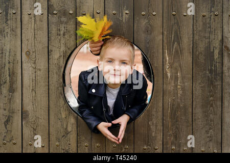 Portrait of happy little boy le kid est à la recherche de la fenêtre en bois rond et souriant Banque D'Images