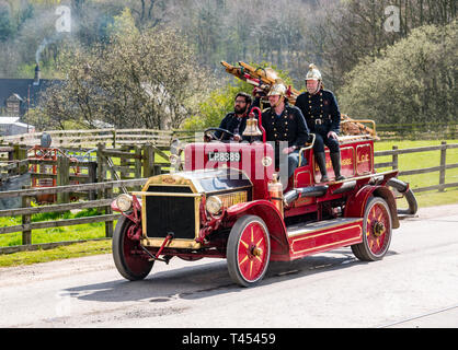 Beamish, comté de Durham, Angleterre, Royaume-Uni, 13 avril 2019. Jour : un vapeur Beamish vintage 1916 Dennis rouge feu ouvert en haut du véhicule moteur avec des hommes habillés en costumes d'époque les pompiers à l'affiche au Musée vivant de Beamish Banque D'Images