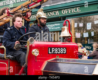 Beamish, comté de Durham, Angleterre, Royaume-Uni, 13 avril 2019. Jour : un vapeur Beamish vintage 1916 Dennis rouge feu ouvert en haut du véhicule moteur avec des hommes habillés en costumes d'époque les pompiers à l'affiche au Musée vivant de Beamish Banque D'Images