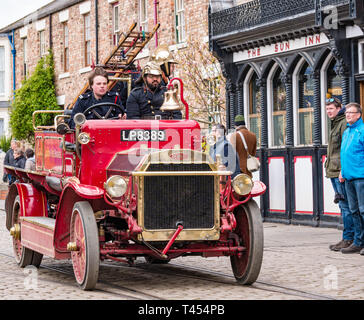 Beamish, comté de Durham, Angleterre, Royaume-Uni, 13 avril 2019. Jour : un vapeur Beamish vintage 1916 Dennis rouge feu ouvert en haut du véhicule moteur avec des hommes habillés en costumes d'époque les pompiers à l'affiche au Musée vivant de Beamish Banque D'Images