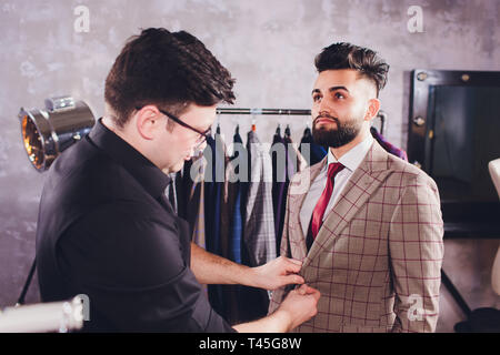 Sur mesure professionnelle mature prise de mesures pour répondre à couture tailors shop. Homme avec un ruban à mesurer occupé. Tissu sur mesure Exclusive Concept. Banque D'Images