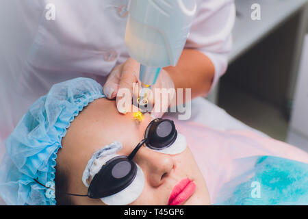 Dépose d'un Laser maquillage permanent sur un visage. Jeune femme libre de recevoir la correction d'un tatouage sur les sourcils. Correction du parc naturel Banque D'Images