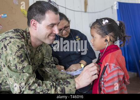 VENCEDOR, Brésil (fév. 27, 2019) Le lieutenant John Sullivan aide un jeune patient dans l'écoute de son coeur avec son stéthoscope lors d'une clinique médicale à Vencedor, Brésil, le 27 février. La visite marque la neuvième et dernière étape de la mission d'un mois par quatre médecins de la Marine américaine et leurs homologues de la marine brésilienne embarquée à bord de navire-hôpital de la marine brésilienne Carlos Chagas NAsH (U 19) pour échanger de l'expertise médicale et d'apporter des soins médicaux aux communautés isolées le long de la rivière Amazone. Banque D'Images