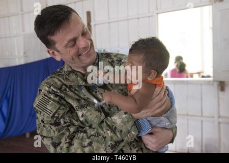 VENCEDOR, Brésil (fév. 27, 2019) Le lieutenant Cmdr. Robert Lennon rencontre un jeune patient lors d'une clinique médicale à Vencedor, Brésil, le 27 février. La visite marque la neuvième et dernière étape de la mission d'un mois par quatre médecins de la Marine américaine et leurs homologues de la marine brésilienne embarquée à bord de navire-hôpital de la marine brésilienne Carlos Chagas NAsH (U 19) pour échanger de l'expertise médicale et d'apporter des soins médicaux aux communautés isolées le long de la rivière Amazone. Banque D'Images