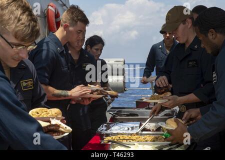 Les marins de la Marine américaine des aliments sont servis au cours d'un repas à bord du destroyer lance-missiles USS Preble (DDG 88) dans la mer de Chine du Sud, le 28 février 2019. L'Preble est déployée sur l'U.S 7e flotte zone d'opérations à l'appui de la sécurité et de la stabilité dans la région Indo-Pacifique. Banque D'Images