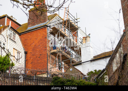 Ouvriers travaillant en hauteur sur des échafaudages weatherboards fixant de nouveaux à un bâtiment, hastings, East Sussex, UK Banque D'Images