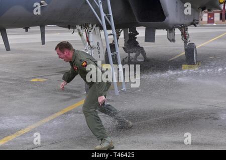Le Lieutenant-colonel de l'US Air Force Eric Haas, 550e Escadron de chasse, esquives d'un jet d'eau d'un extincteur après son dernier vol dans un F-15 Eagle 2 Mars, 2019 à Kingsley Field à Klamath Falls, Oregon. Il est tradition de pulvériser les pilotes avec de l'eau et du champagne à la suite de leur dernier vol. Banque D'Images