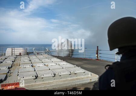 Océan Atlantique (11 mars 2019) Un marin regarde un cinq pouces canon est tiré pendant une démonstration de tir réel à bord du croiseur lance-missiles USS Hue (CG 66). La ville de Hue était en cours pour une croisière où les amis et les familles de l'équipage est monté à bord de l'expérience de la vie sur un croiseur. Banque D'Images