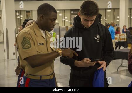 Le sergent marine. Capot Jasper aide Virgile Beineix obtenez plus d'information sur les occasions dans le Corps des marines pendant un collège juste à Norfolk, en Virginie, le 13 mars. Grâce à un partenariat avec le milieu est de l'Athletic Conference, le Marine Corps reconnaît et célèbre les étudiants-athlètes qui affichent de fortes qualités de leadership par leur engagement à travailler dur à la fois dans et hors de la classe. Jasper est un recruteur à RSS Chesapeake. Beineix assiste à Granby l'école secondaire. Banque D'Images