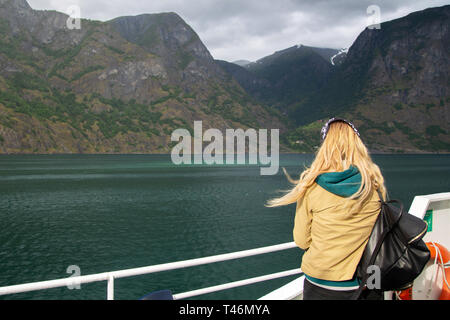 Jeune femme avec un sac à dos sur le pont du ferry se penche sur les fjords norvégiens. Femme blonde sur un bateau touristique admire la nature de la Norvège. A vous Banque D'Images