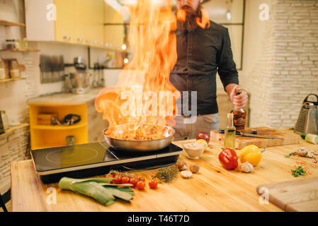 Male chef cooking meat avec vetables on fire Banque D'Images