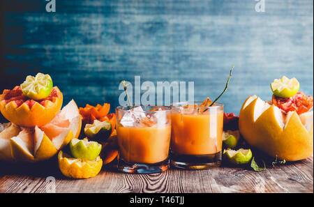 Mélanger le jus de citron dans les verres sur table avec divers agrumes ingrédients : citron vert, pamplemousse, orange, mandarine, citron et pomelo au mur sombre zone Banque D'Images