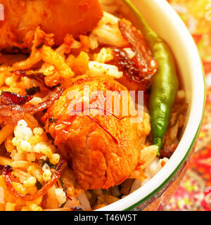 Close up morceau de poulet tikka et brins de safran Biryani indien servi avec du yogourt raita tomate fond blanc. Focus sélectif. Image carrée. Banque D'Images