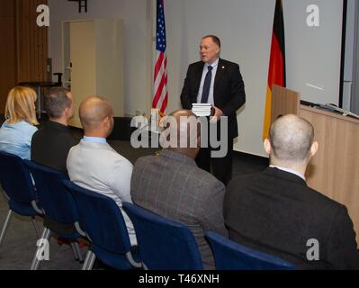 GARMISCH-PARTENKIRCHEN, Allemagne (12 mars 2019) - Retraité U.S. Marine Corps Colonel James Howcroft, du centre Marshall directrice de programme pour le programme sur le terrorisme et d'études de sécurité, les mains à la "lutte contre le terrorisme transnational" livre à l'avenir sept participants au cours de la cérémonie de remise des diplômes de langue anglaise Cours d'amélioration 12 mars ici. Ce livre sera utilisé quotidiennement au cours de TSPT 19-07 et a été édité par l'équipe du Centre Marshall TSPT. Le professeur James se flétrissent et Sam Mullins a édité le livre, qui a des contributions de TSPT alumni. C'ELEC est un programme sur mesure Banque D'Images