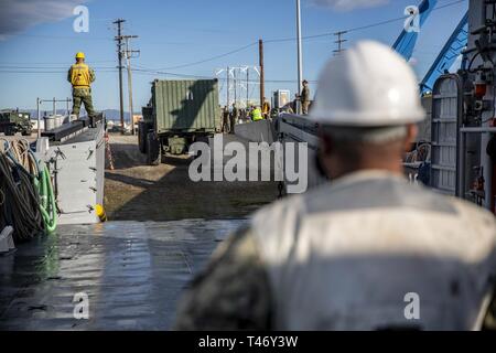 Les marins américains, guide un tracteur sur pneus en caoutchouc, direction articulée, Multi-Purpose (TRAM) transportant un conteneur sur un utilitaire de débarquement au cours des opérations de mouvement maritime à Port Hueneme, Californie, dans le cadre de l'exercice Pacific Blitz 19, 12 mars. PacBlitz19 est conçu pour former des Marines et marins dans des opérations de la force maritime place préalable et vise à augmenter les niveaux de compétence, l'expansion de la coopération et de renforcer les capacités maritimes. Banque D'Images