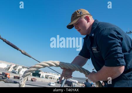 La Marine américaine Technicien Cryptologic (technique) 2e classe Tristin Anderson, du Liban, de l'Ohio, gère une ligne sur le fo'c'sle de missiles de l'USS Stockdale (DDG 106) alors qu'au départ de Manama, Bahreïn, le 12 mars 2019. L'Stockdale est déployé sur le 5e flotte américaine zone d'opérations à l'appui des opérations navales pour assurer la stabilité et la sécurité maritime dans la région Centrale, reliant la Méditerranée et le Pacifique à travers l'ouest de l'Océan indien et trois points d'étranglement stratégiques. Banque D'Images