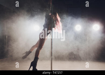 Belle pole dancer en blouson de cuir sur pylône. Banque D'Images