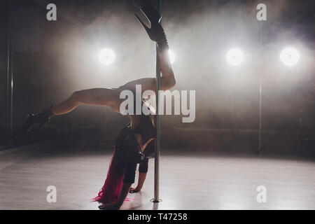 Belle pole dancer en blouson de cuir sur pylône. Banque D'Images