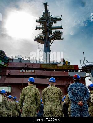 NEWPORT NEWS, Virginie (15 mars 2019) marins affectés à la classe Nimitz porte-avions USS George Washington (CVN 73) regarder en haut le mât principal nouvellement installé au cours de la cérémonie à pas de mât sur George Washington's d'envol. Mast-le pas à pas est une pratique de l'antiquité grecque et romaine de mettre des pièces au pied du mât d'un navire en construction. George Washington est en cours de révision (complexe de ravitaillement RCOH) au chantier naval Newport News. RCOH est un projet de quatre ans presque réalisée qu'une seule fois pendant une durée de 50 ans du transporteur qui comprend la durée de vie de l'équipage du navire de ravitaillement deux re Banque D'Images