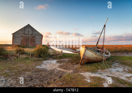 Coucher du soleil à l'ancienne grange du charbon sur Thornham Harbour sur la côte de Norfolk Banque D'Images