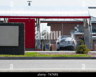 Cute femme laver sa voiture dans un lave-auto manuel Banque D'Images