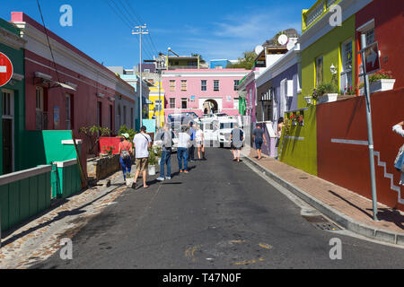 Groupe ou d'une foule de touristes ou de personnes dans la rue ou le chemin à l'extérieur de maisons colorées le quartier résidentiel historique de Bo Kaap à Cape Town Banque D'Images