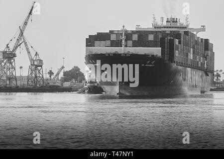 Photo en noir et blanc du porte-conteneurs, YM UNANIMITÉ, navigue à travers l'étroit canal principal de Los Angeles jusqu'au port de Los Angeles, en Californie Banque D'Images