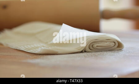 Maison de pâte fillo isolé sur la table farinée.Rolling pin sur l'arrière-plan flou Banque D'Images