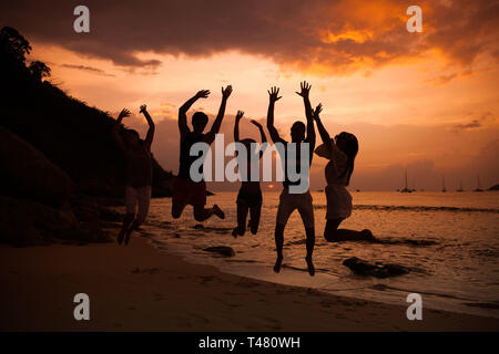 Groupe de gens heureux en mer plage au coucher du soleil Banque D'Images
