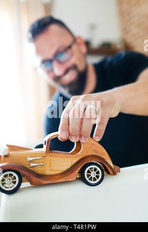Retour dans l'enfance, l'homme jouant avec voiture jouet en bois - jouets classique Banque D'Images