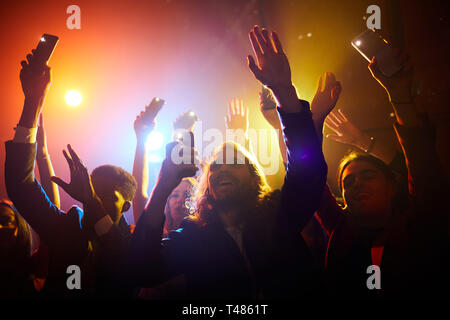 Heureux fans waving gadgets avec lampes de poche allumé Banque D'Images