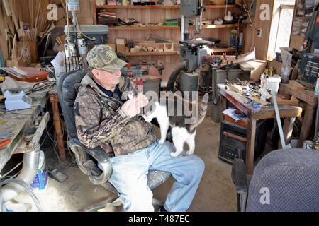 Man dans son atelier avec sa mascotte et animal chat dans le Maryland USA Banque D'Images