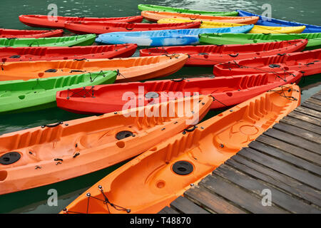 Canoës multicolores amarré à la jetée en bois sur fond nature Banque D'Images