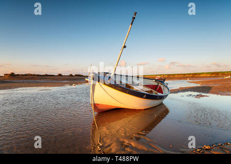 Un voilier en bois baignés dans la lumière du soir à Burnham Overy Staithe sur le littoral de Norfolk Banque D'Images