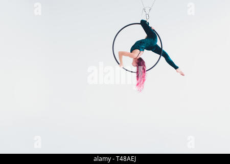 Une jeune fille exécute les éléments acrobatiques dans l'anneau de l'air. Performances de prise de vue Studio sur fond blanc. Banque D'Images