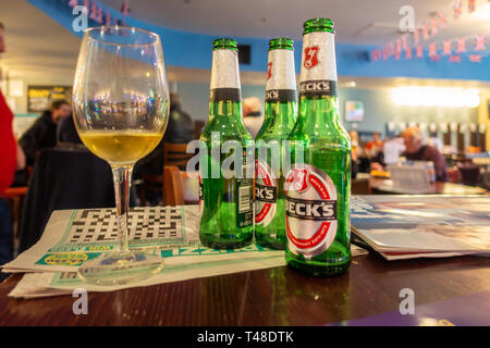 Les bouteilles de bière en verre et un verre de vin à gauche sur une table dans un pub. Banque D'Images