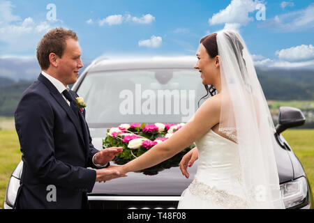 Mariée et le marié en face de la voiture de mariage Banque D'Images