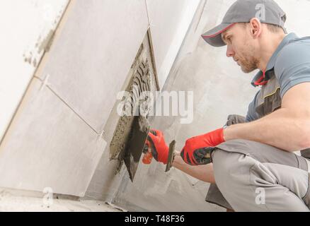 Salle de bains carreaux de céramique d'installation. Young Construction Worker dans la trentaine. Banque D'Images