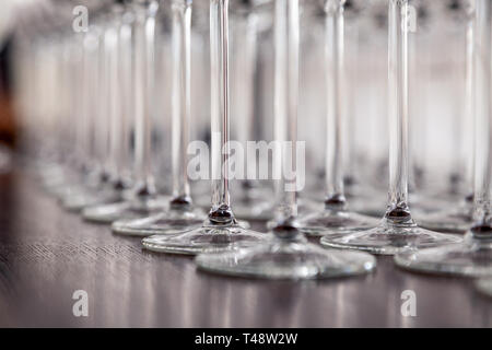 De nombreux verres à vin cristal transparent stand dans la rangée sur l'étagère en bois brun du rack. Vue de côté. Le concept de la dégustation de whisky, le brandy, le port Banque D'Images