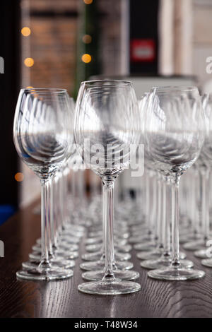 De nombreux verres à vin cristal transparent stand dans la rangée sur l'étagère en bois brun du rack. Vue de côté. Le concept de la dégustation de whisky, le brandy, le port Banque D'Images