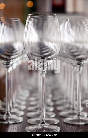 De nombreux verres à vin cristal transparent stand dans la rangée sur l'étagère en bois brun du rack. Vue de côté. Le concept de la dégustation de whisky, le brandy, le port Banque D'Images