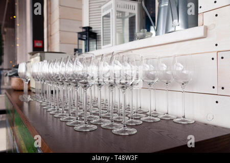 De nombreux verres à vin cristal transparent stand dans la rangée sur l'étagère en bois brun du rack. Vue de côté. Le concept de la dégustation de whisky, le brandy, le port Banque D'Images