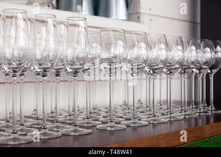 De nombreux verres à vin cristal transparent stand dans la rangée sur l'étagère en bois brun du rack. Vue de côté. Le concept de la dégustation de whisky, le brandy, le port Banque D'Images