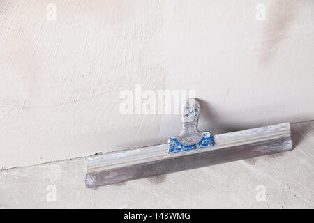 La spatule se trouve à proximité d'une paroi gris dans une maison en construction. La construction du concept d'une maison de campagne, chalet, garage Banque D'Images