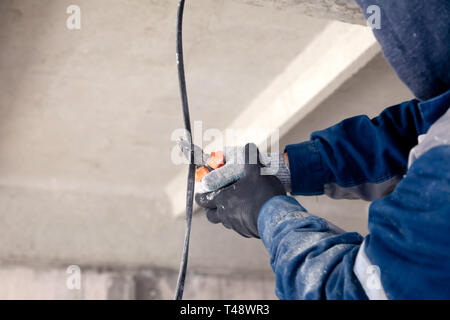 Builder travailleur électriques, mord avec une pince à câble électrique noir. Concept un travail dangereux, haute tension, ingénieur électricien, Banque D'Images