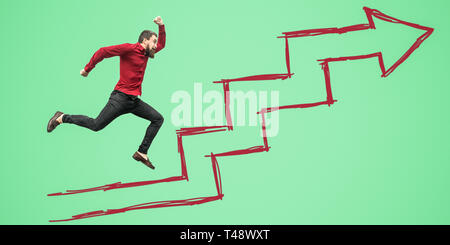 Vue latérale pleine longueur portrait of businessman barbu un red shirt sauter ou voler sur fond vert drawed Étapes de croissance flèche. succès, mot Banque D'Images