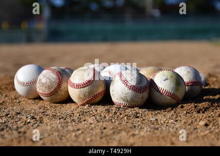 Photo en gros plan d'un groupe de balles de jeu utilisé sur un terrain de baseball, un jour ensoleillé, avec un terrain de baseball à l'arrière-plan Banque D'Images